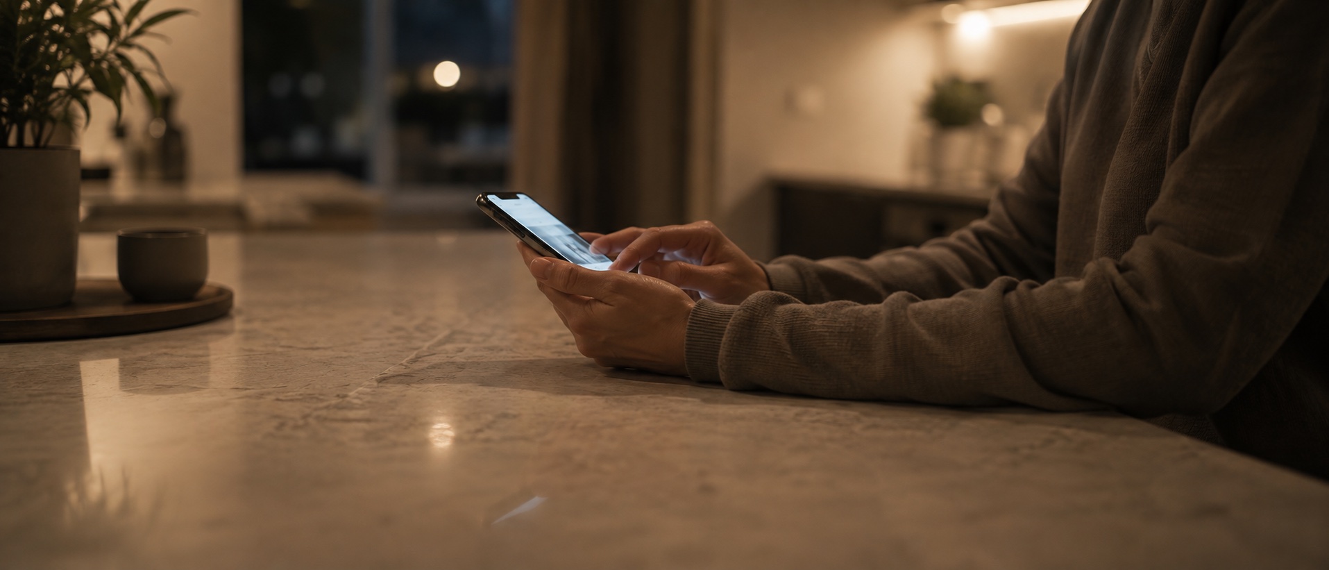 A shopper using their phone at a kitchen counter in the evening